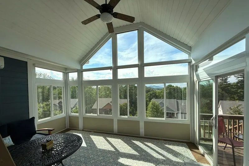 Motorized roller shades on a sunroom wall of windows with a peaked gable