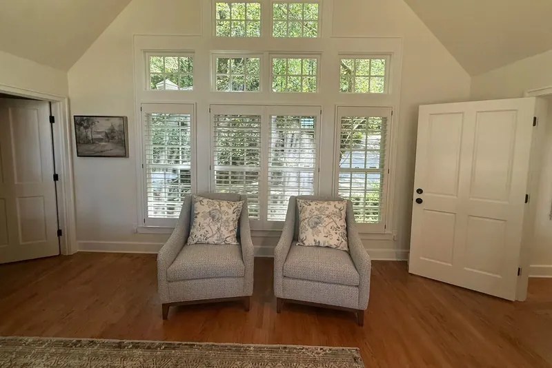 Plantation shutters on a wall of tall windows in a vaulted sitting room