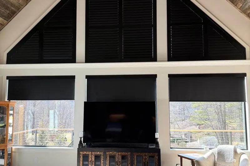 Room darkening roller shades on tall great room windows under a vaulted ceiling, with the mountains outside