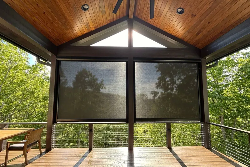 Motorized exterior solar screens lowered on a covered deck with a mountain view